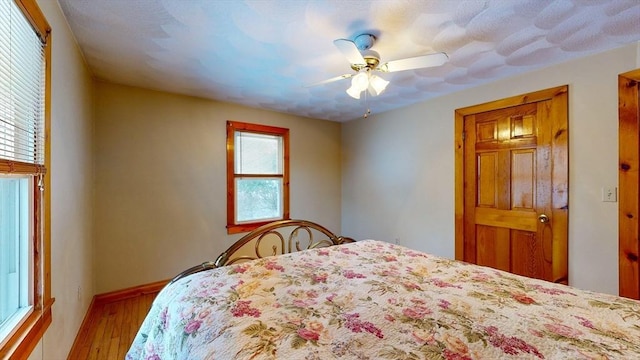 bedroom with ceiling fan, baseboards, and wood finished floors