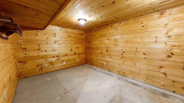 empty room with a sauna, unfinished concrete floors, wooden ceiling, and wooden walls