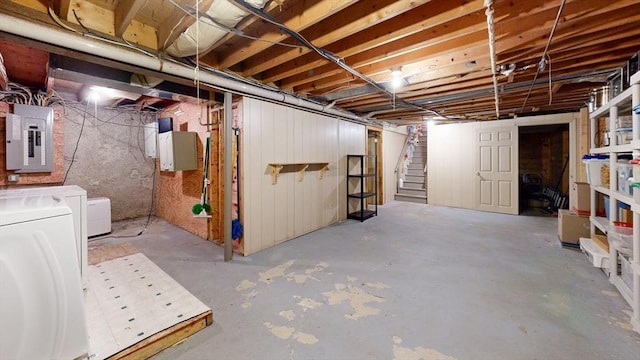 unfinished basement with electric panel, stairway, and washer and dryer