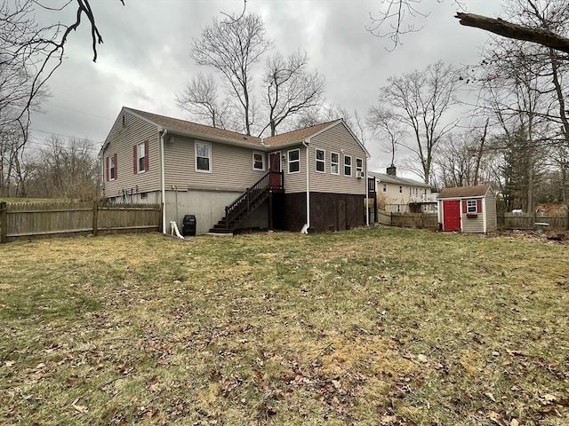 rear view of house featuring a storage shed, a yard, an outdoor structure, and fence