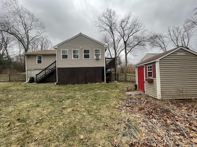 rear view of property featuring a yard, an outbuilding, fence, and stairs