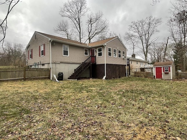 back of house featuring a yard, fence, a storage unit, and an outbuilding