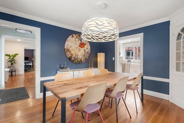 dining area featuring baseboards, light wood finished floors, and crown molding