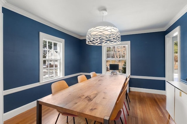 dining space with baseboards, wood finished floors, a wealth of natural light, and crown molding