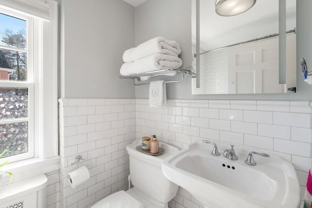 bathroom with a sink, tile walls, and toilet