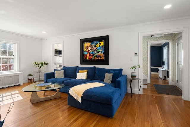 living area with crown molding, baseboards, wood finished floors, and radiator