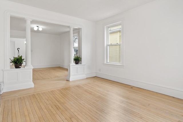 unfurnished room with decorative columns, baseboards, and hardwood / wood-style floors