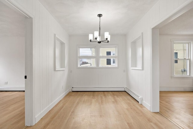 unfurnished dining area featuring light wood-style floors, baseboards, a baseboard heating unit, and a notable chandelier