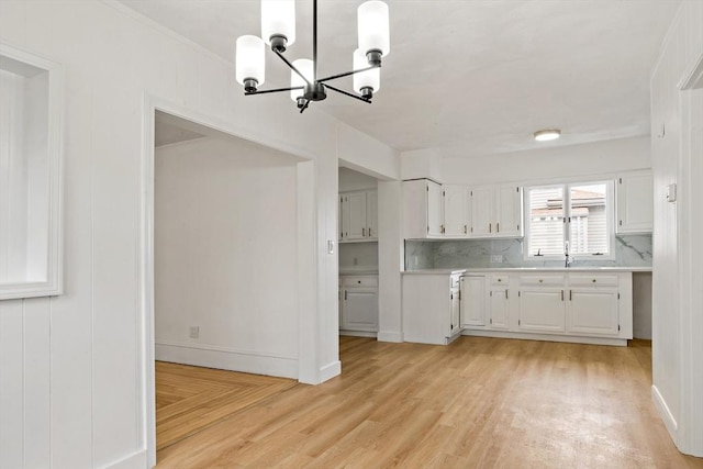 kitchen with white cabinets, light wood-type flooring, light countertops, and a sink