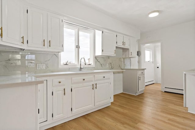 kitchen with a wealth of natural light, a baseboard radiator, white cabinetry, and a sink