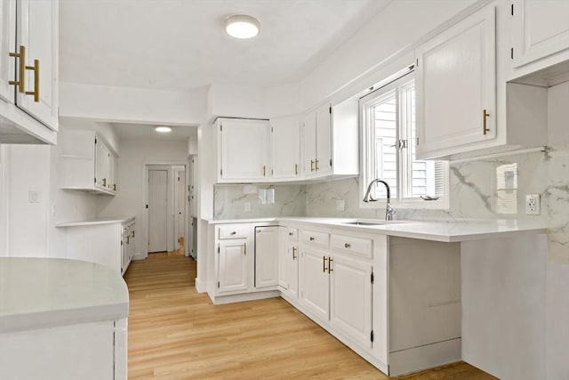 kitchen with white cabinetry, a sink, and light wood finished floors