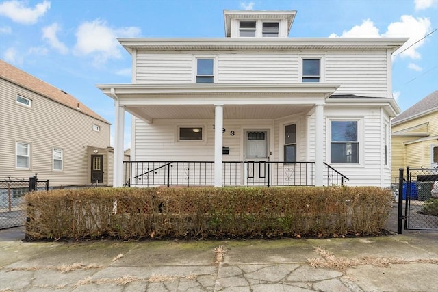 american foursquare style home featuring a porch and fence