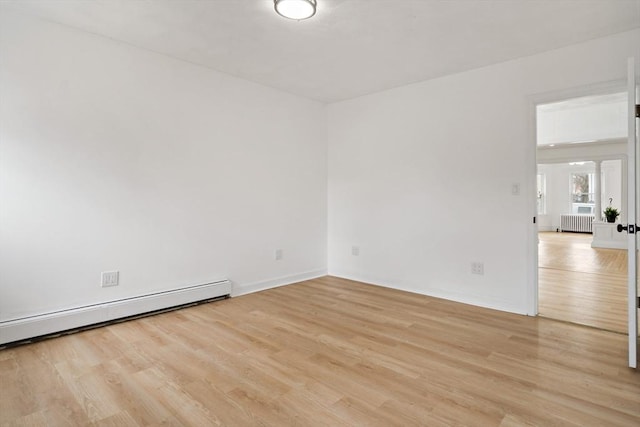 empty room featuring a baseboard heating unit, radiator heating unit, light wood-style flooring, and baseboards