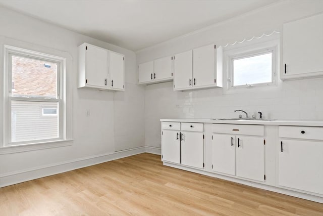 kitchen with light wood-style floors, white cabinetry, and a sink