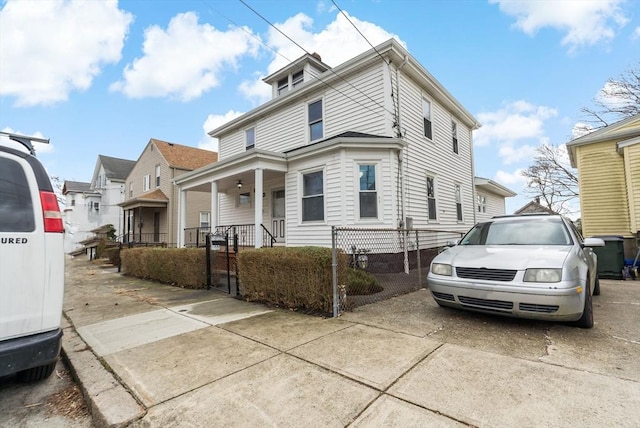 american foursquare style home featuring covered porch and a fenced front yard