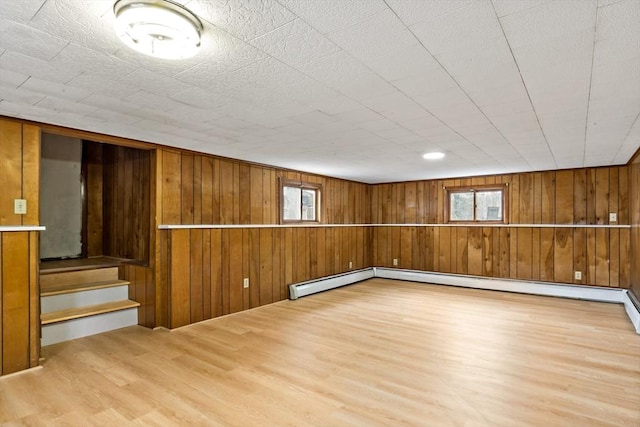 basement with a healthy amount of sunlight, wood walls, stairway, and wood finished floors