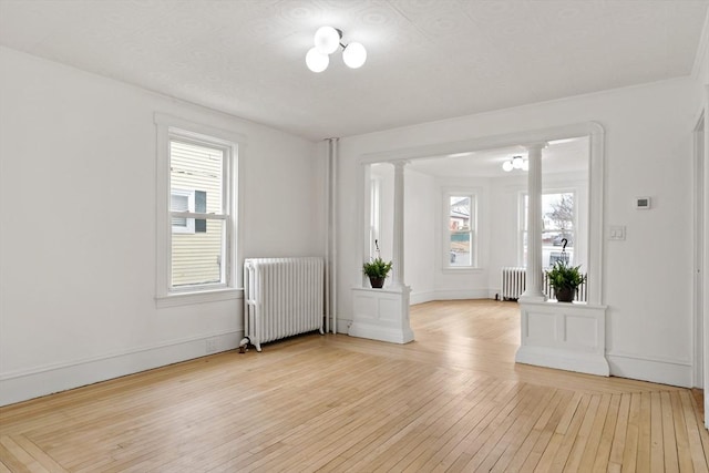 foyer entrance featuring a healthy amount of sunlight, radiator heating unit, and ornate columns