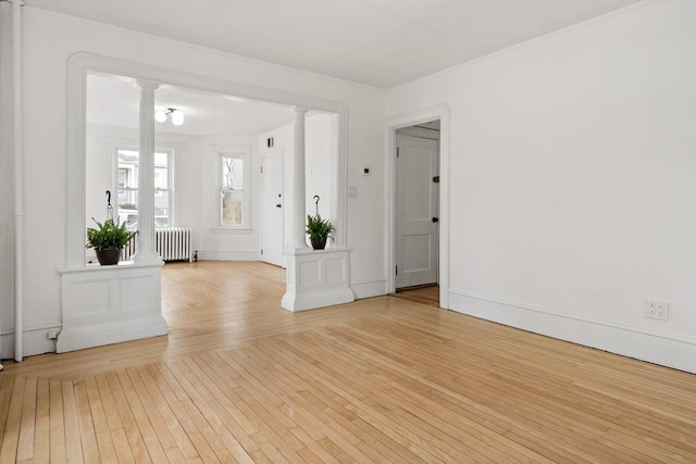 empty room featuring radiator, ornate columns, and hardwood / wood-style flooring