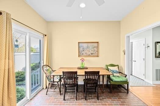dining area with a ceiling fan, baseboards, and brick floor