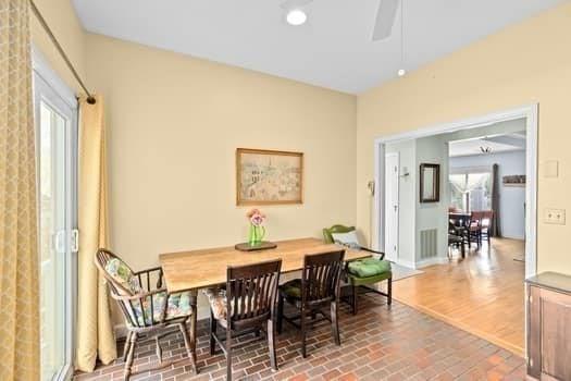 dining area with baseboards, brick floor, ceiling fan, and visible vents