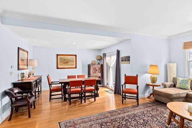 living area with baseboards, ornamental molding, and light wood-style flooring