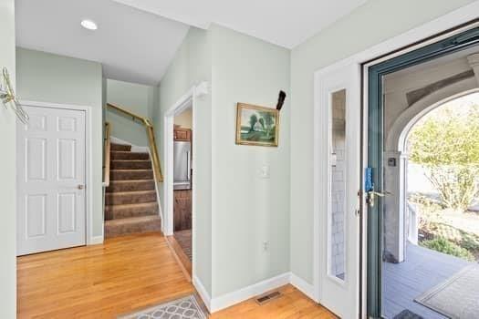 entrance foyer featuring baseboards, light wood finished floors, stairs, and visible vents