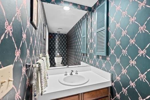 bathroom with vanity and wallpapered walls