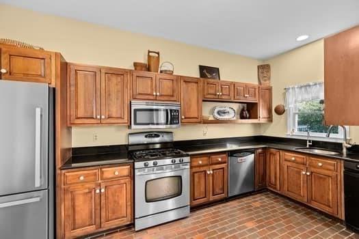 kitchen featuring brown cabinets, dark countertops, and appliances with stainless steel finishes