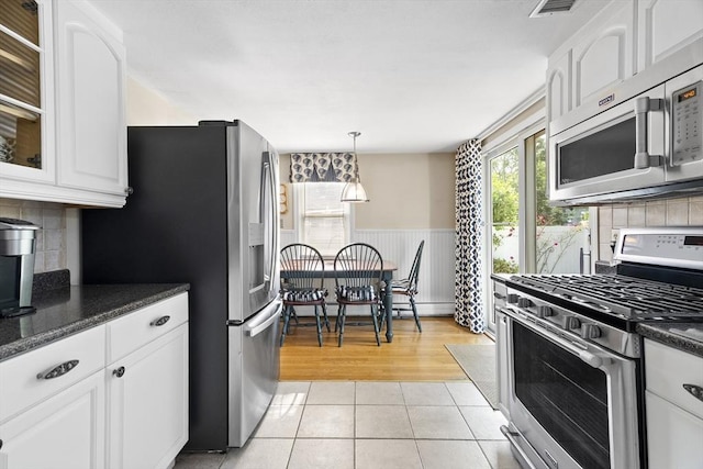 28 Chestnut St, Falmouth, MA 02536 - kitchen featuring appliances with stainless steel finishes, white cabinets, wainscoting, light tile patterned flooring, and decorative backsplash