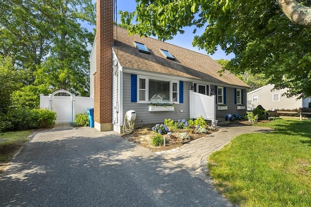 28 Chestnut St, Falmouth, MA 02536 - view of front facade featuring a chimney, a gate, a shingled roof, and asphalt driveway