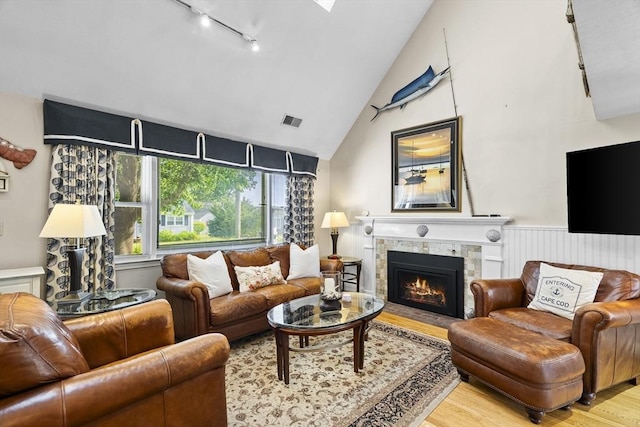 28 Chestnut St, Falmouth, MA 02536 - living area with track lighting, wood finished floors, high vaulted ceiling, a tile fireplace, and wainscoting