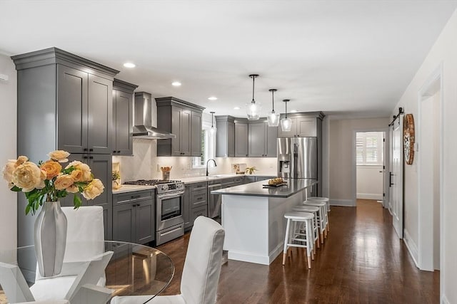 32 Gilman Rd, Billerica, MA 01862 - kitchen with appliances with stainless steel finishes, wall chimney exhaust hood, gray cabinets, baseboards, and a kitchen bar