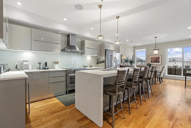 kitchen with wall chimney range hood, modern cabinets, appliances with stainless steel finishes, and gray cabinetry