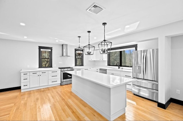 kitchen featuring light countertops, visible vents, stainless steel appliances, a sink, and wall chimney range hood