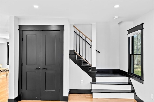 stairway featuring wood finished floors, recessed lighting, and a wealth of natural light