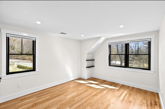 empty room with baseboards, visible vents, light wood-style flooring, and a healthy amount of sunlight