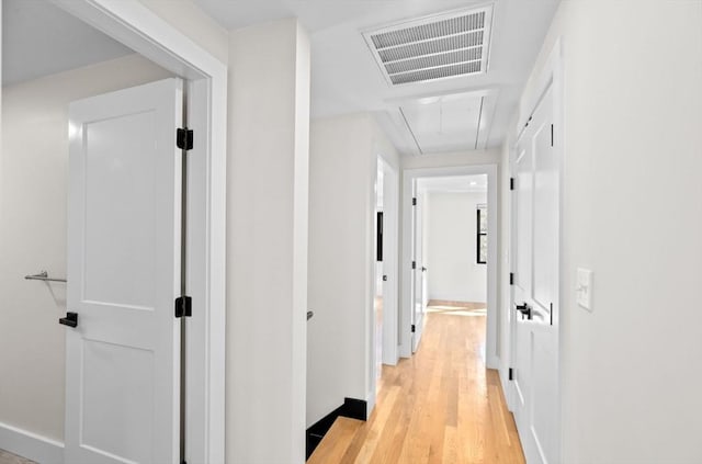 hall with light wood-style floors, baseboards, attic access, and visible vents