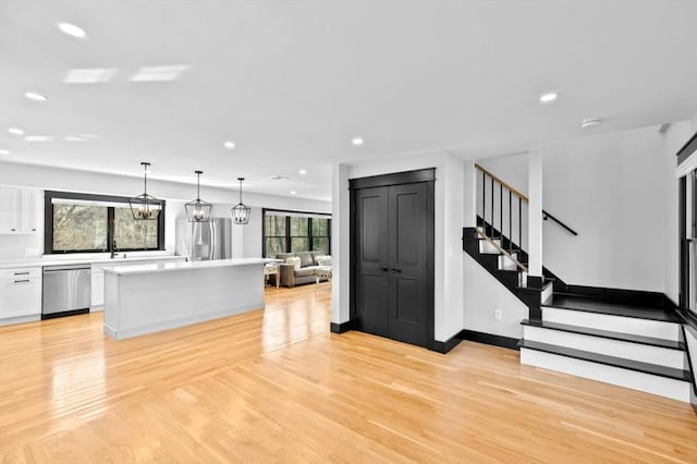 kitchen with white cabinetry, a kitchen island, stainless steel appliances, and light wood finished floors