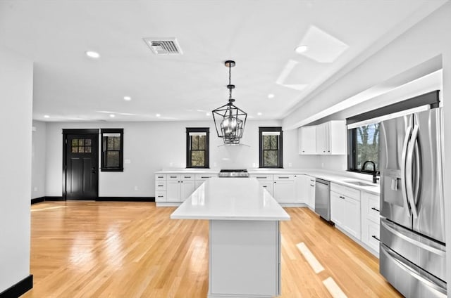 kitchen with plenty of natural light, a center island, a sink, visible vents, and appliances with stainless steel finishes