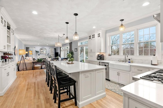 kitchen featuring appliances with stainless steel finishes, light countertops, a sink, a center island, and open floor plan