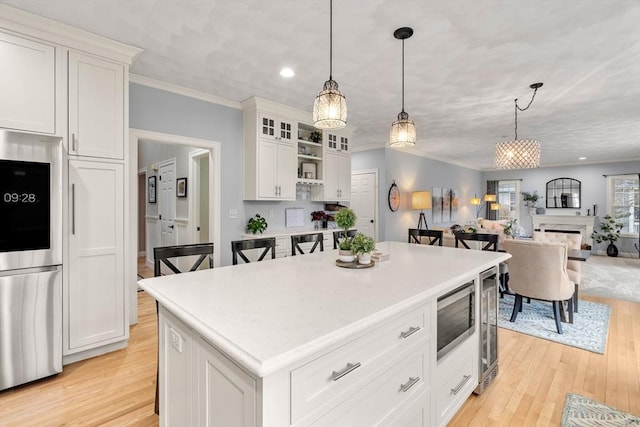 kitchen featuring appliances with stainless steel finishes, decorative light fixtures, light wood finished floors, and white cabinets