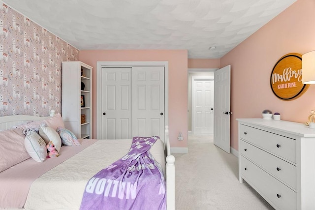 bedroom featuring a closet, baseboards, wallpapered walls, and light carpet