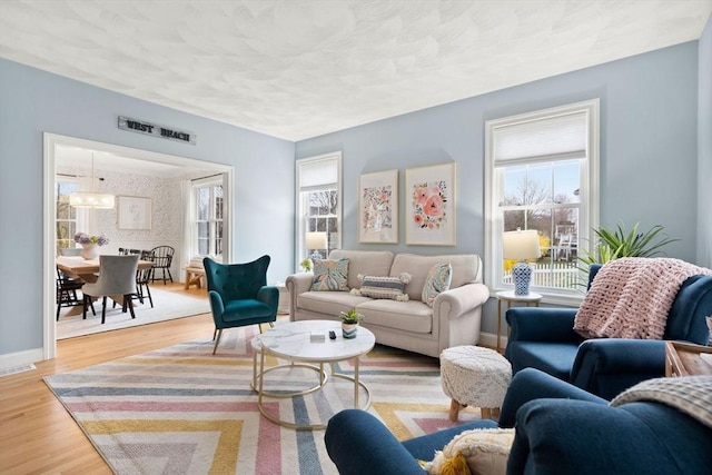living area featuring a textured ceiling, visible vents, wood finished floors, and baseboards