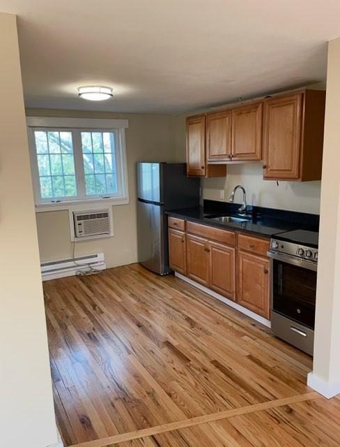 35 Parker Rd Unit 26, Falmouth, MA 02536 - kitchen featuring appliances with stainless steel finishes, a sink, a baseboard heating unit, a wall unit AC, and dark countertops