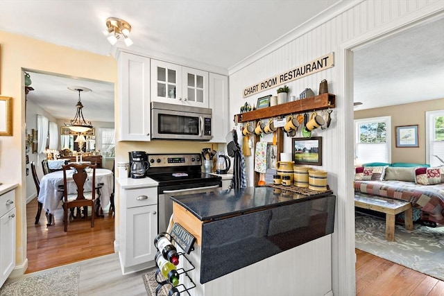 39 Bennets Neck Dr, Bourne, MA 02559 - kitchen with appliances with stainless steel finishes, light wood-type flooring, white cabinets, and glass insert cabinets