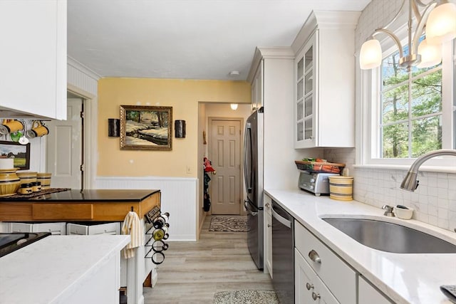 39 Bennets Neck Dr, Bourne, MA 02559 - kitchen with stainless steel dishwasher, white cabinetry, light wood-type flooring, glass insert cabinets, and wainscoting