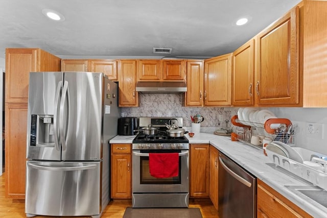 kitchen featuring decorative backsplash, light hardwood / wood-style flooring, and stainless steel appliances