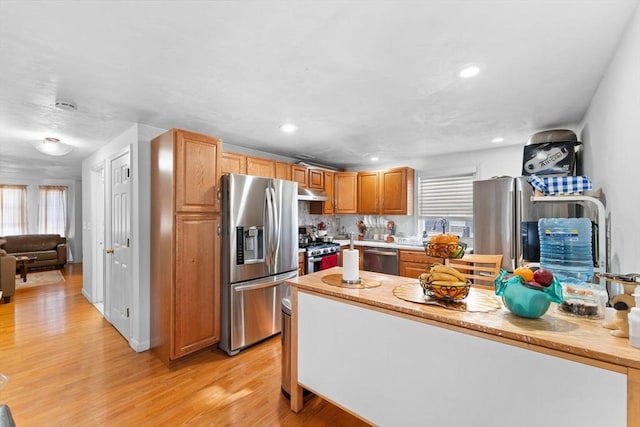 kitchen featuring decorative backsplash, stainless steel appliances, light hardwood / wood-style flooring, and a wealth of natural light