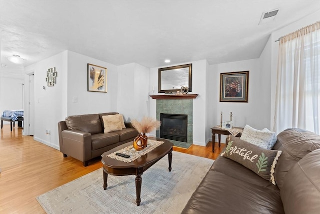 living room featuring light hardwood / wood-style floors, a wealth of natural light, and a tiled fireplace