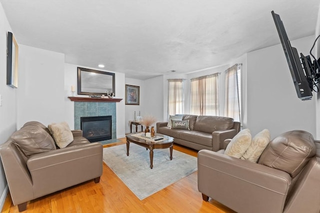 living room featuring a tile fireplace and light hardwood / wood-style flooring